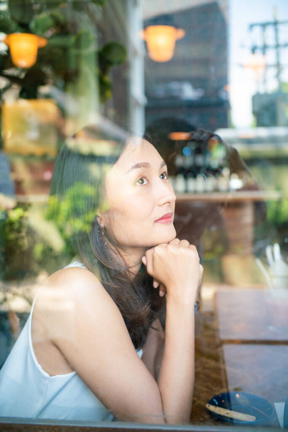Hermosas mujeres asiáticas sentadas en una cafetería urbana mirando por la ventana, mujeres de negocios - Foto, Imagen