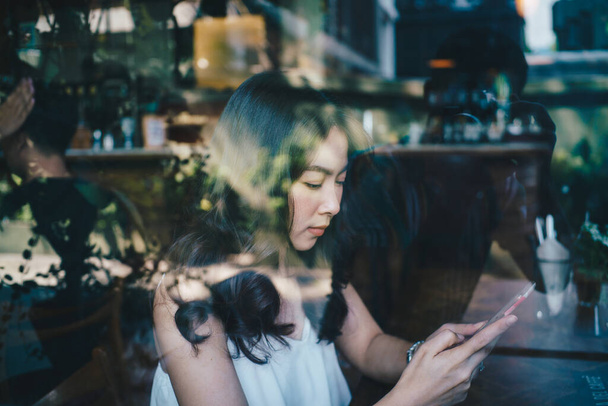 Business Aasian naiset käyttävät älypuhelin istuu kahvilassa päivä valo - Valokuva, kuva