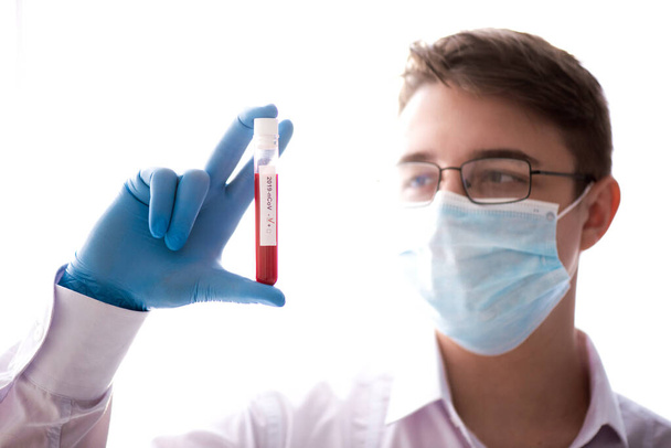 Rurka testowa w męskiej ręce, lekarz w masce medycznej trzymający fiolkę z czerwonym płynem. Koncepcja próbki krwi, diagnostyka koronawirusów, badania medyczne. - Zdjęcie, obraz
