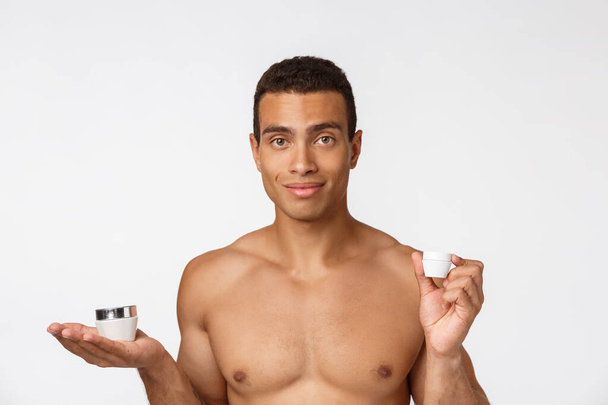 Photo of shirtless african american man smiling and holding cream isolated over white background - Foto, Bild