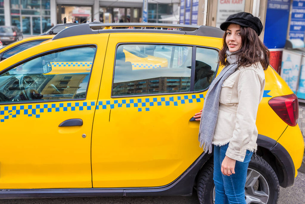 Mooi jong meisje opent of sluit deur van een gele taxi met haar hand.Traveler vrouw levensstijl Concept. - Foto, afbeelding