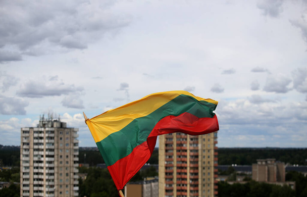 Литовський прапор махає триколором над містом. - Фото, зображення
