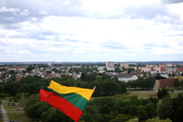 A bandeira lituana está acenando em tricolor sobre a cidade
 - Foto, Imagem