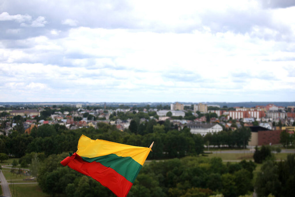 A bandeira lituana está acenando em tricolor sobre a cidade
 - Foto, Imagem