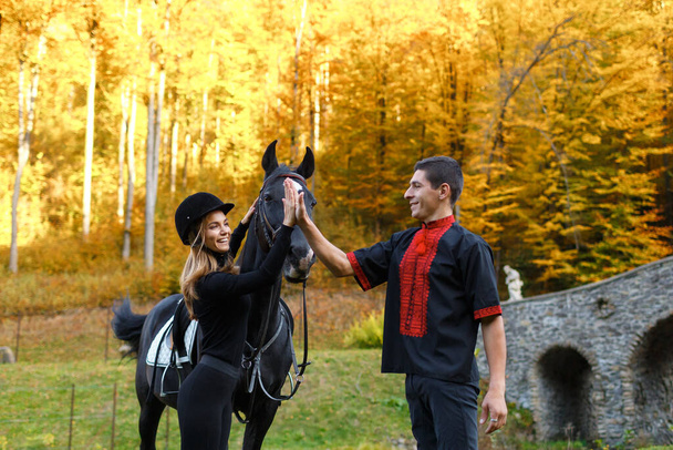 girl riding a horse in park in Autumn near lake in the mountains. horseman and horsewoman on horse galloping. jockey teach woman to ride. equestrian sport concept. training to ride on horse. vacation - Photo, Image