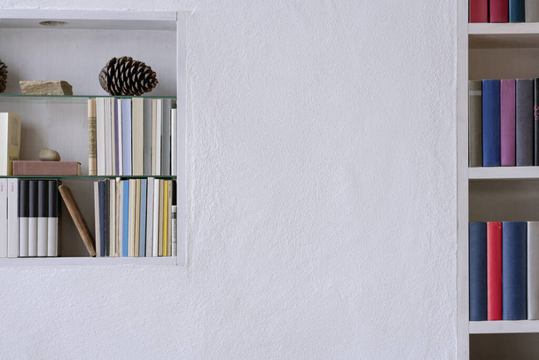 Detail of bookshelves with nice decoration in a white pure plastered wall with copy space - Fotó, kép