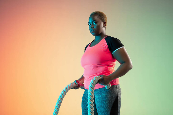 Young african-american plus size female models training on gradient background - Foto, immagini