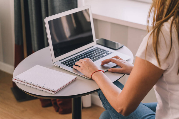Молодая женщина работает или учится дома со своим ноутбуком. Концепция сетей и новых технологий
. - Фото, изображение