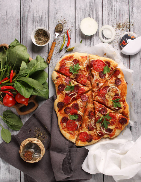 Italian cuisine. Pizza with sausages on a wooden background, background image, copy space, pizza with hands - Foto, afbeelding