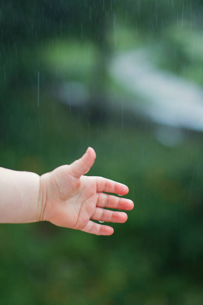 A kisgyerek fogja az esőcseppeket. Eső háttér - Fotó, kép