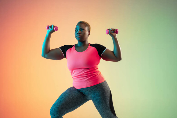 Young african-american plus size female models training on gradient background - Foto, Imagen