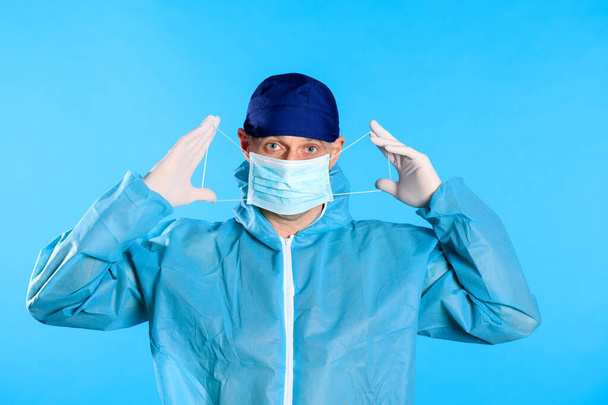 Mann im weißen Dekontaminationsanzug zieht medizinische Handschuhe an - Foto, Bild