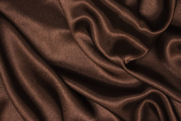Gladde elegante bruine zijde of satijnen luxe stoffen textuur kan worden gebruikt als abstracte achtergrond. Gekromde stof Gekromd aan de zijkant. - Foto, afbeelding