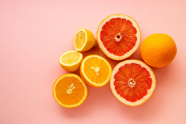 Various halves of citrus fruits on a pink background - Foto, Imagem
