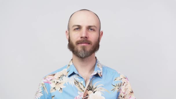 Портрет спокойного бородатого мужчины, смотрящего в камеру в гавайской рубашке, изолированного на белом фоне. Концепция эмоций
. - Кадры, видео