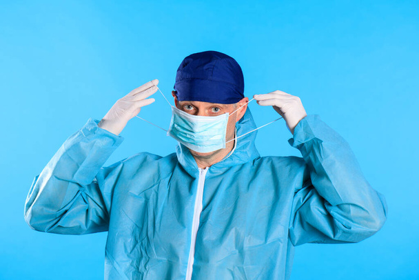 Mężczyzna w białym kombinezonie odkażającym zakładający rękawiczki medyczne - Zdjęcie, obraz