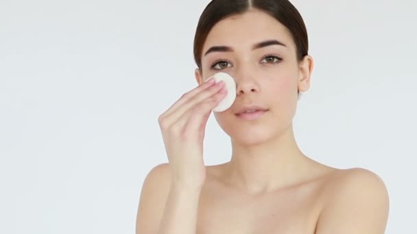 Close up shot of beautiful young woman wiping her bare face with cotton pad, then looking at camera. Skin treatment concept video, touching skin, skin concept video. 4K , Slow motion - Felvétel, videó