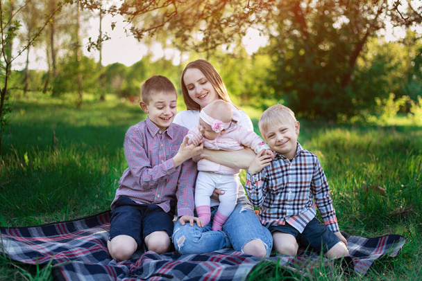 Щасливий великий сімейний пікнік на природі. Красива молода мати і троє дітей
 - Фото, зображення