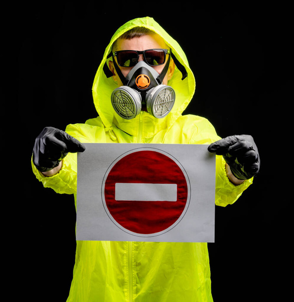  Covid-19 coronavirus infection concept.  Man in protective respirator and gloves holding stop sign over black background - Photo, Image