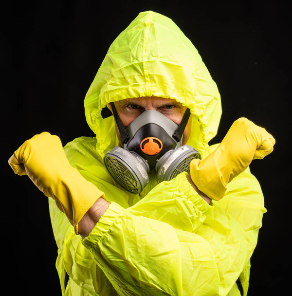 Coronavirus and healthcare concept. Respiratory protection. Portrait of young man in respirator and gloves over black background - Photo, Image