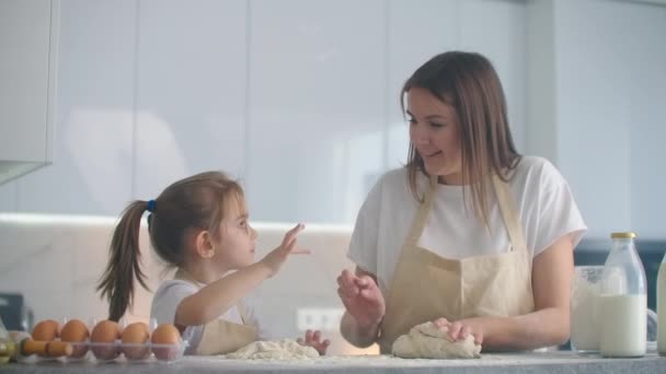 Matka a dcera vaří s plísní v kuchyni. Matka a dcera drží těsto ve tvaru srdce. Sculpt těsto s rukama, aby polotovary pro pizzu nebo koláč, sušenky - Záběry, video