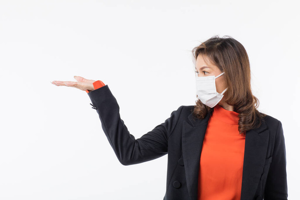 Businesswoman in black suit wearing surgical protective hygiene mask on face point finger to blank somewhere. Idea for preventing health from virus outbreak and tell information about the disease. - Foto, immagini