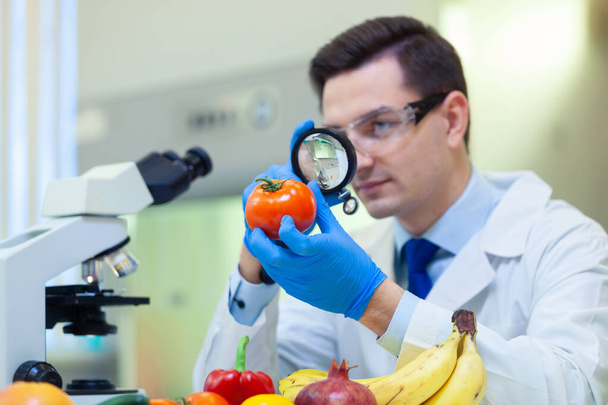 Labormitarbeiter untersucht Obst und Gemüse und führt Analysen auf Pestizide und Nitrate durch. - Foto, Bild