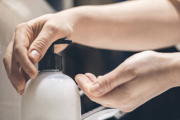 Jovem caucasiano mão mulher pressionando garrafa de sabão de plástico, como, para fazer uma lavagem de mãos, foco seletivo
 - Foto, Imagem