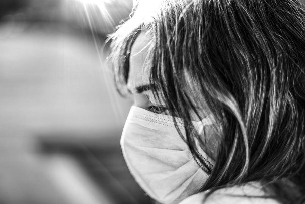 Корона Вирус. Больной коронной женщиной, смотрящей в окно и носящей защиту от дыхания и выздоравливающей от болезни дома. Пациент изолирован для предотвращения инфекции
 - Фото, изображение