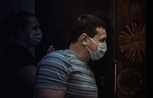 Άνδρας και γυναίκα με ιατρικές μάσκες στέκονται κοντά στην πόρτα ενάντια στο COVID-19 - Φωτογραφία, εικόνα