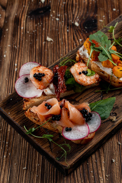 Primer plano de plato de bruschetta: con pera y jamón de parma, salmón y queso, calabaza al horno y queso ricotta
 - Foto, imagen