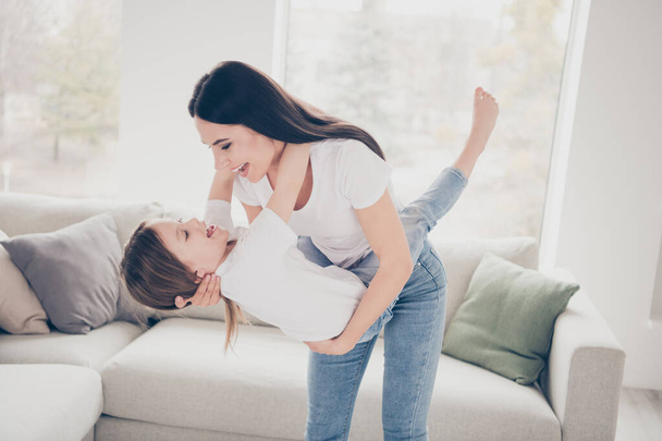 Profile photo of nice cute little girl young charming mommy holding her hands swinging playing laughing out loud spend free time weekend together indoors home house - 写真・画像