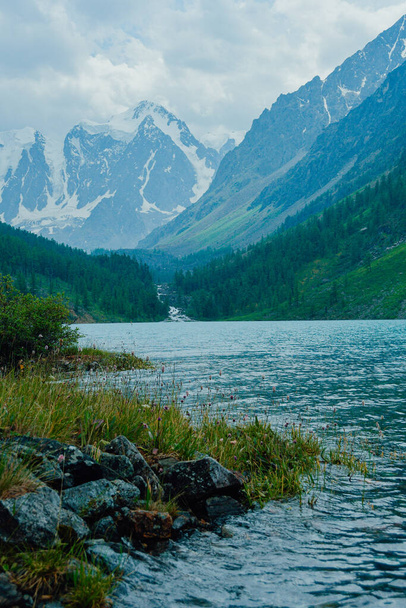 lake with peaks and rock ridge on horizon, hiking and climbing in mountains, stone cliff above blue water - Фото, зображення
