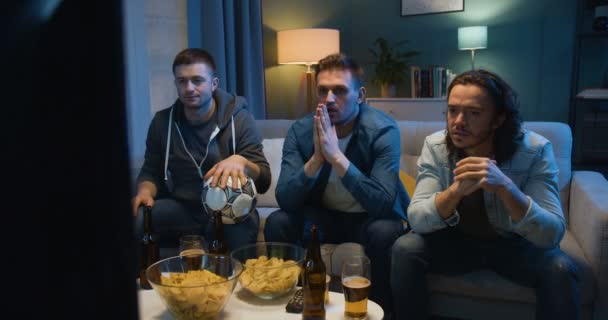 Caucasian guys sport fans sitting on sofa at home in front of TV and worrying for their favorite football team. Loosing in match concept. Dissapointment after lost in game. - Footage, Video