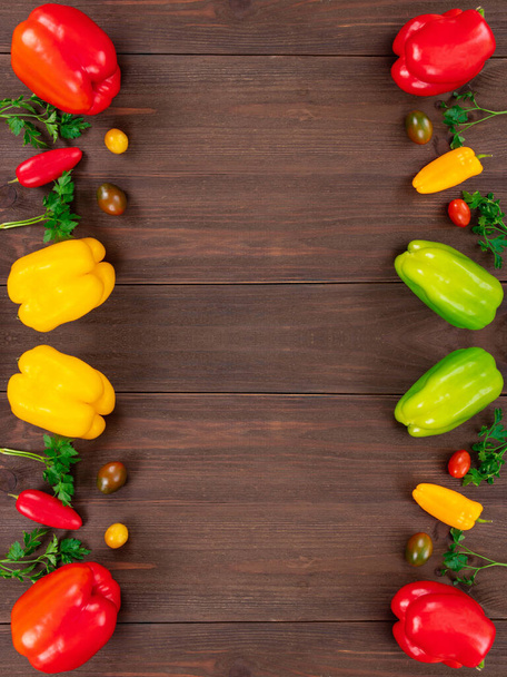 Alimentos saudáveis, moldura lateral vertical em fundo de madeira com espaço de cópia. Tomates cereja, pimentas e folhas de salsa, vista superior
 - Foto, Imagem