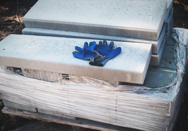 Reparação de laje de concreto Estrada e duas luvas de borracha azul de trabalho construção de peças
 - Foto, Imagem