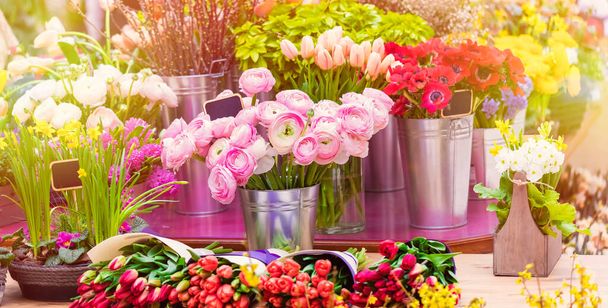 Colorful showcase in a florist store. Flowers in big vases. Bouquet of the Flower of Ranculus (pion rose) pink color, red anemones and tulips. Flower business - Фото, зображення