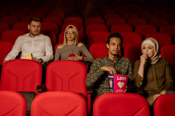 Gülen arkadaşların sinemada oturup film izlediği patlamış mısır yediği ve havalandırılmış tatlı su içtiği görüntüler.. - Fotoğraf, Görsel