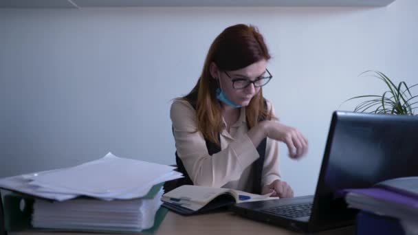gyönyörű nő orvosi maszk dolgozik személyes számítógépen egy modern irodában, beteg női üzleti alkalmazott rossz egészségügyi köhögés miatt vírus vagy fertőzés, karantén - Felvétel, videó