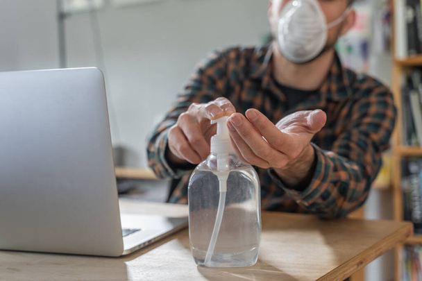 Coronavirus. Man working from home wearing protective mask. quarantine for coronavirus wearing protective mask. Working from home. Cleaning her hands with sanitizer gel. Thermometer fever inspection. - Fotografie, Obrázek