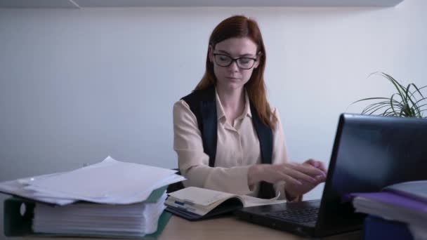 pilný pracovní den, hezká žena v brýlích pro vidění se podívá na obrazovku monitoru a píše informace do notebooku během kancelářské práce, pak sundá brýle, zvládání stresu - Záběry, video