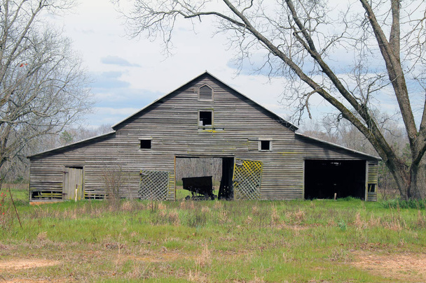 eine alte stillgelegte Bauernscheune mit bewölktem Himmel und Feld - Foto, Bild