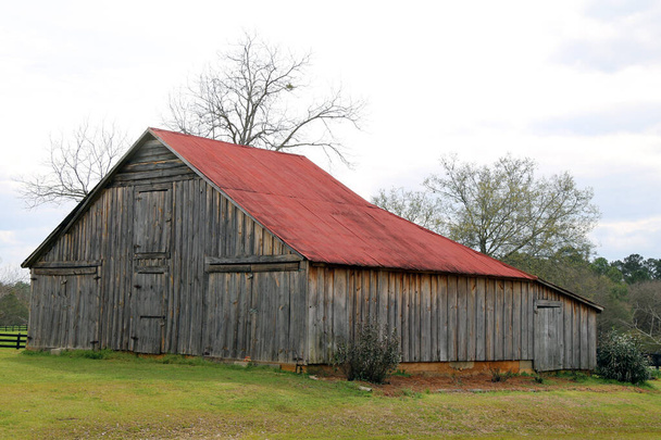 a retro farm barn with a red roof in an empty field - Photo, Image
