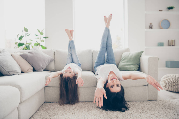 Full body view photo of cute adorable candid mommy and her kid have fee time vacation lay divan upside down raise hands legs bare foot in house room - Fotografie, Obrázek