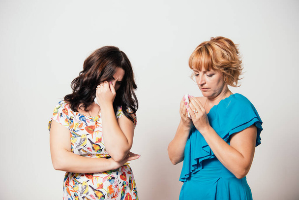 Two women weep against studio background - Foto, imagen