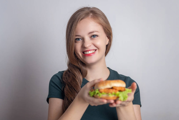 Mosolygó fiatal kaukázusi nő lány gazdaság eszik csirke burger - Fotó, kép