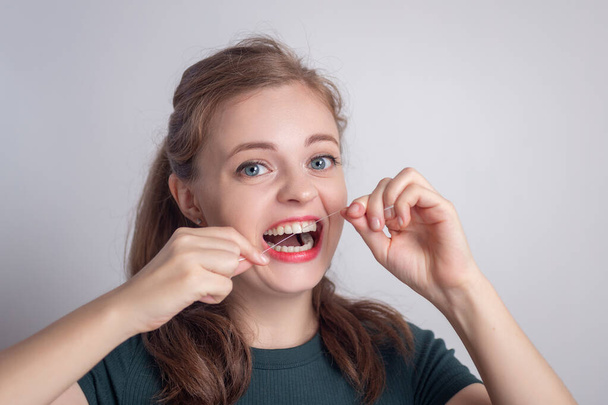 Смішна усміхнена молода біла дівчина використовує зубну нитку
 - Фото, зображення