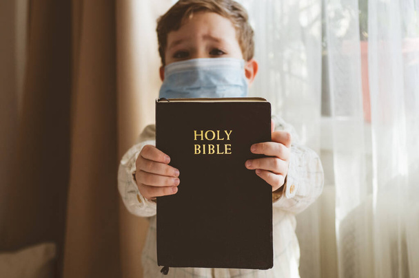 Coronavirus covid-19. Çocuğun elinde bir İncil var. İncil okumaları ve dualar. Barış, umut kavramı - Fotoğraf, Görsel