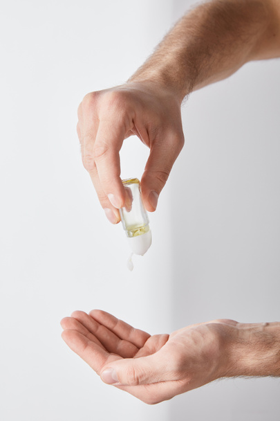 cropped view of adult man using hand sanitizer on white background - Photo, Image