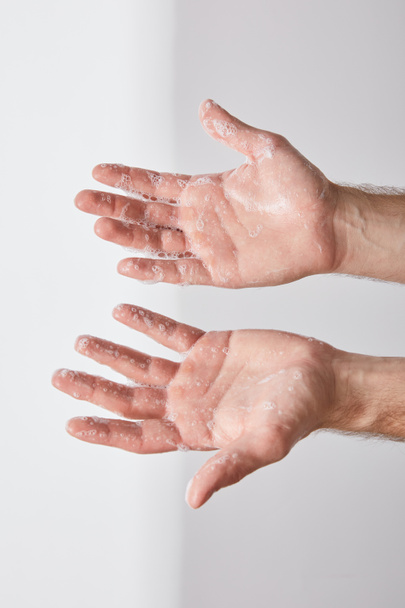 partial view of man showing hands with soap foam on grey background background - Fotoğraf, Görsel